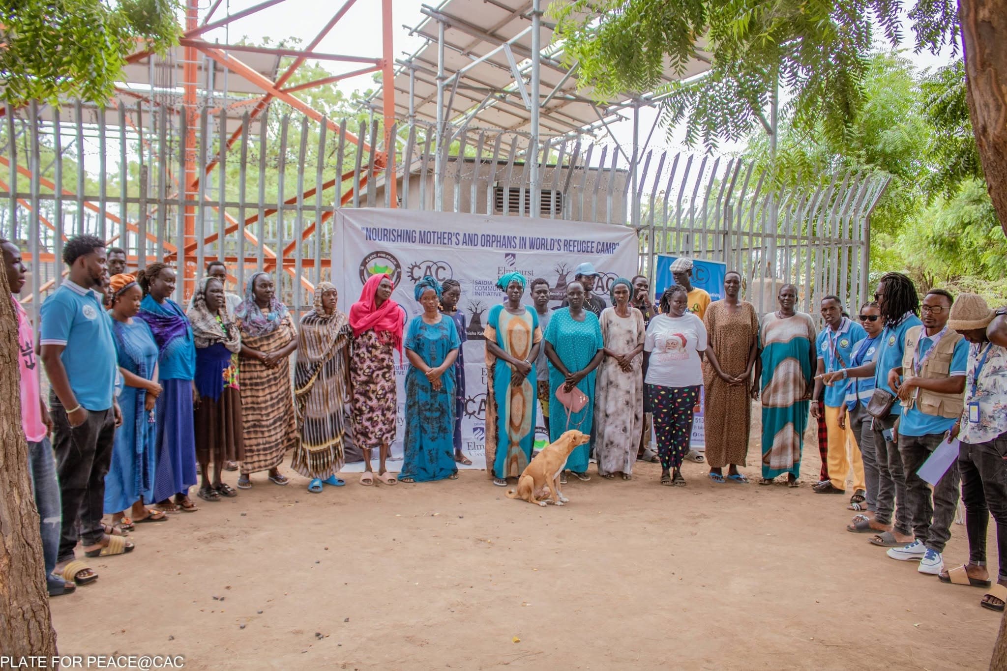 Creative Arts Center team members and community members standing together in front of a project banner